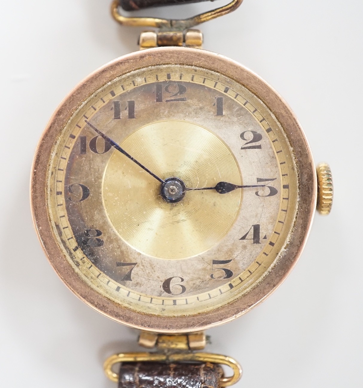 A lady's early 20th century 9ct gold wrist watch, with Arabic dial and RolWatchCo (Wilsdorf & Davis) case, movement unsigned, on associated leather strap, case diameter 26mm, gross weight 17.5 grams.